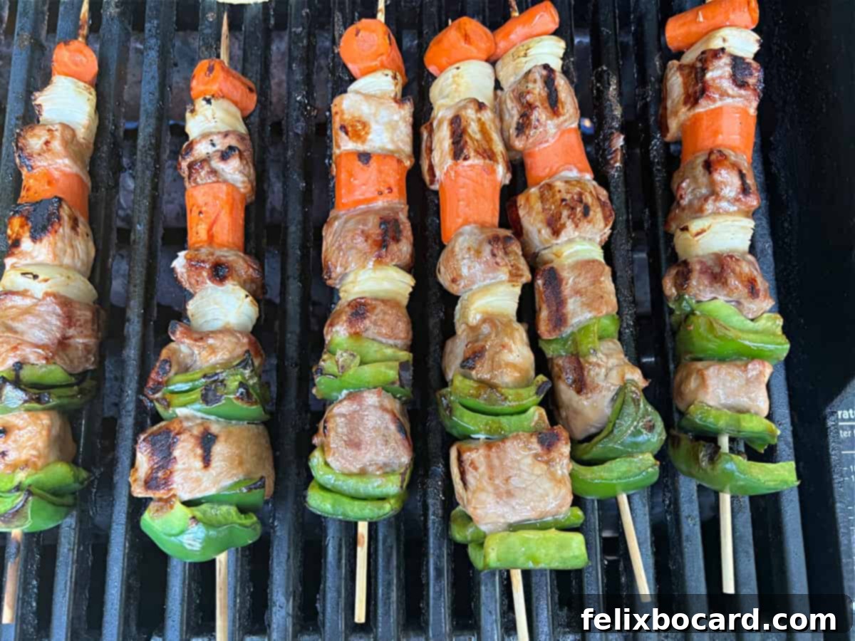 Sweet and sour pork kabobs cooking on the grill, basted with delicious sauce.