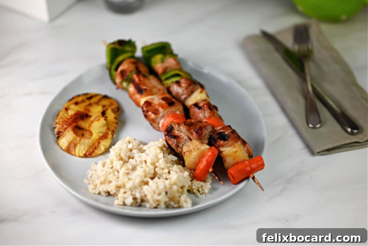 Plate of sweet and sour pork kabobs with rice, ready to be enjoyed.