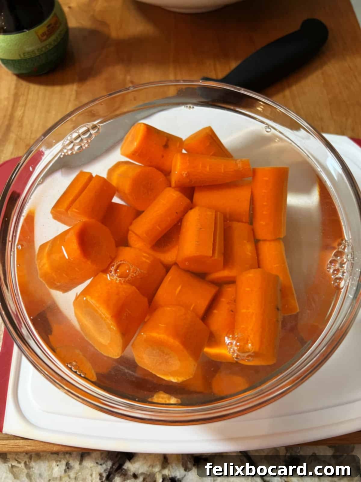 Bowl of carrot chunks immersed in water, ready for pre-cooking.