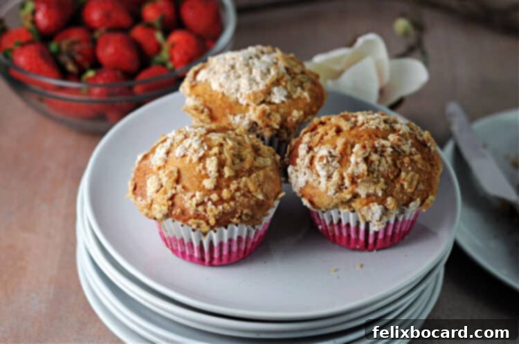 Three delicious strawberry muffins on a white plate, ready to eat.