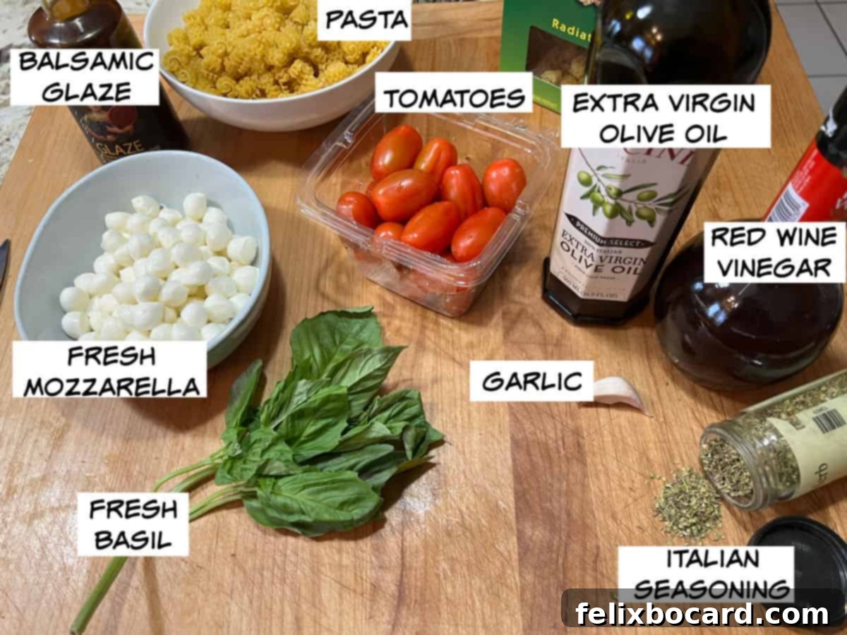 Collection of fresh ingredients for Caprese pasta salad: dry pasta, grape tomatoes, olive oil, red wine vinegar, garlic, Italian seasoning, fresh basil, fresh mozzarella, and balsamic glaze.