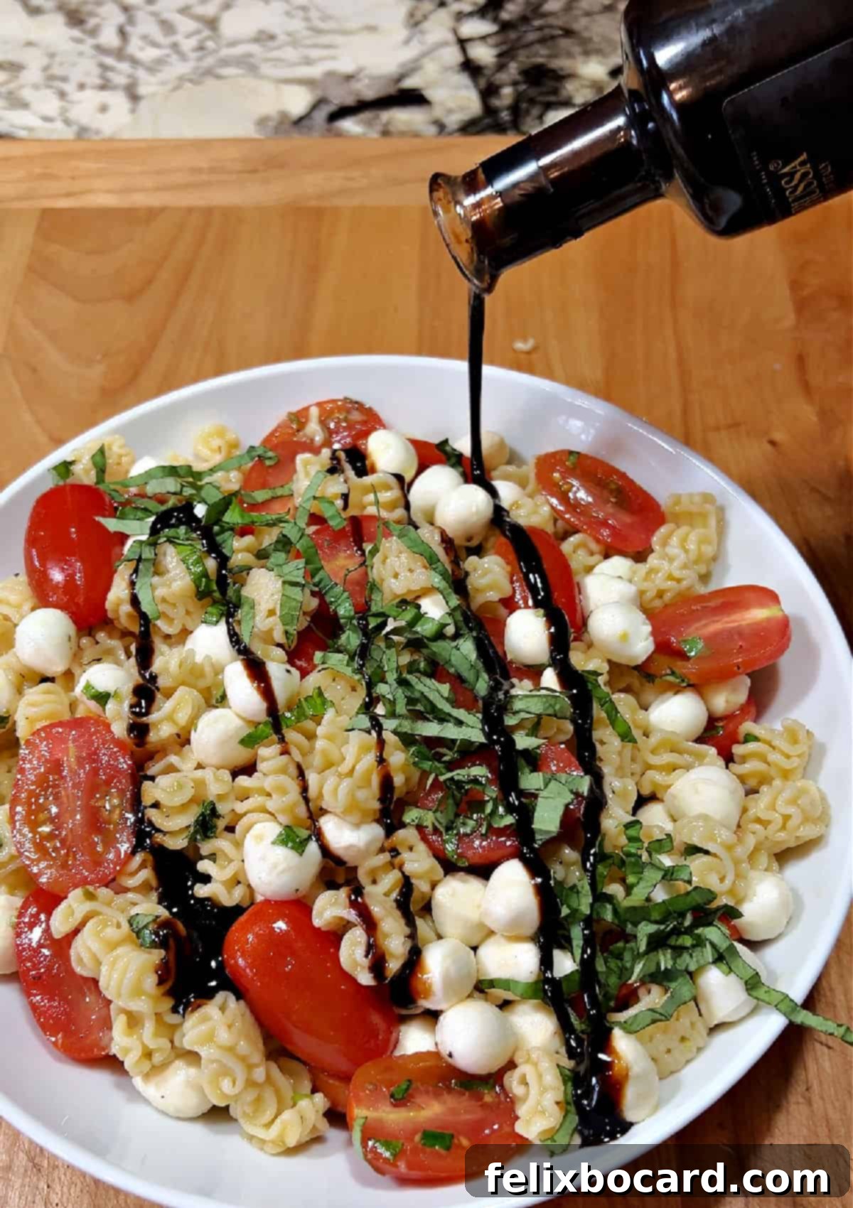 Drizzling balsamic glaze over the vibrant Caprese pasta salad.