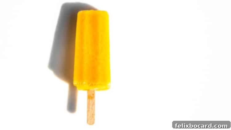 A vibrant orange Creamsicle ice pop against a crisp white background, symbolizing the refreshing flavors of summer.