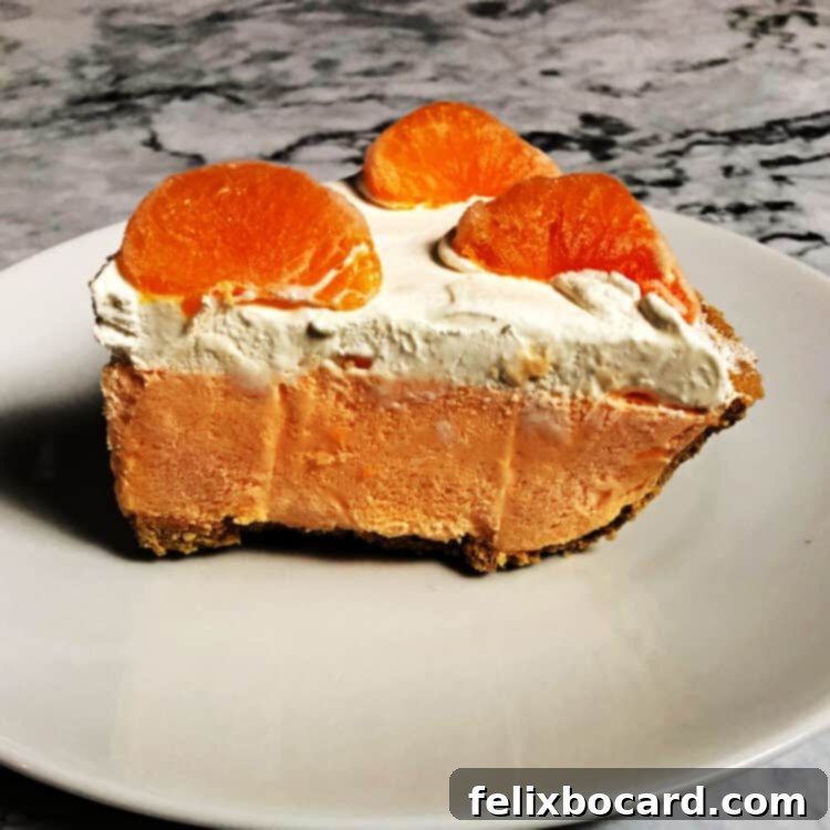 A pristine slice of orange Creamsicle pie, showcasing its creamy layers and perfectly set filling, served on a white plate.