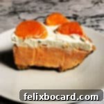A delectable slice of Creamsicle pie on a pristine white plate, garnished with fresh mandarin oranges, ready to be enjoyed.