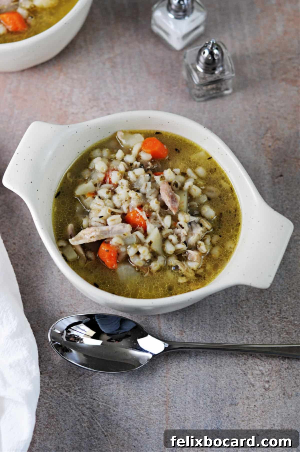 Bowl of Instant Pot Chicken and Barley Soup, garnished with fresh herbs.