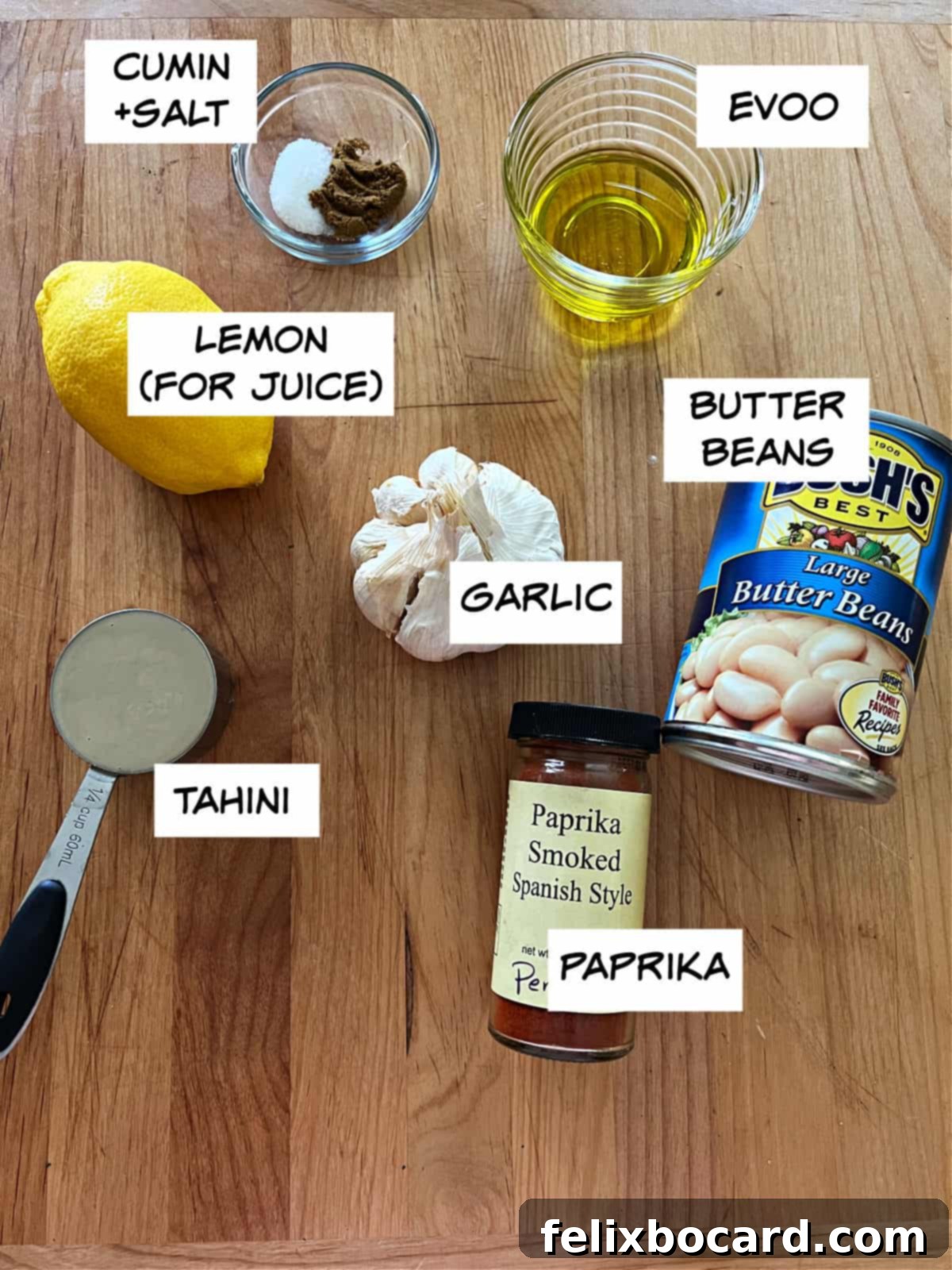 Ingredients for butter bean hummus: lemon, spices, butter beans, garlic, and tahini displayed with labels.