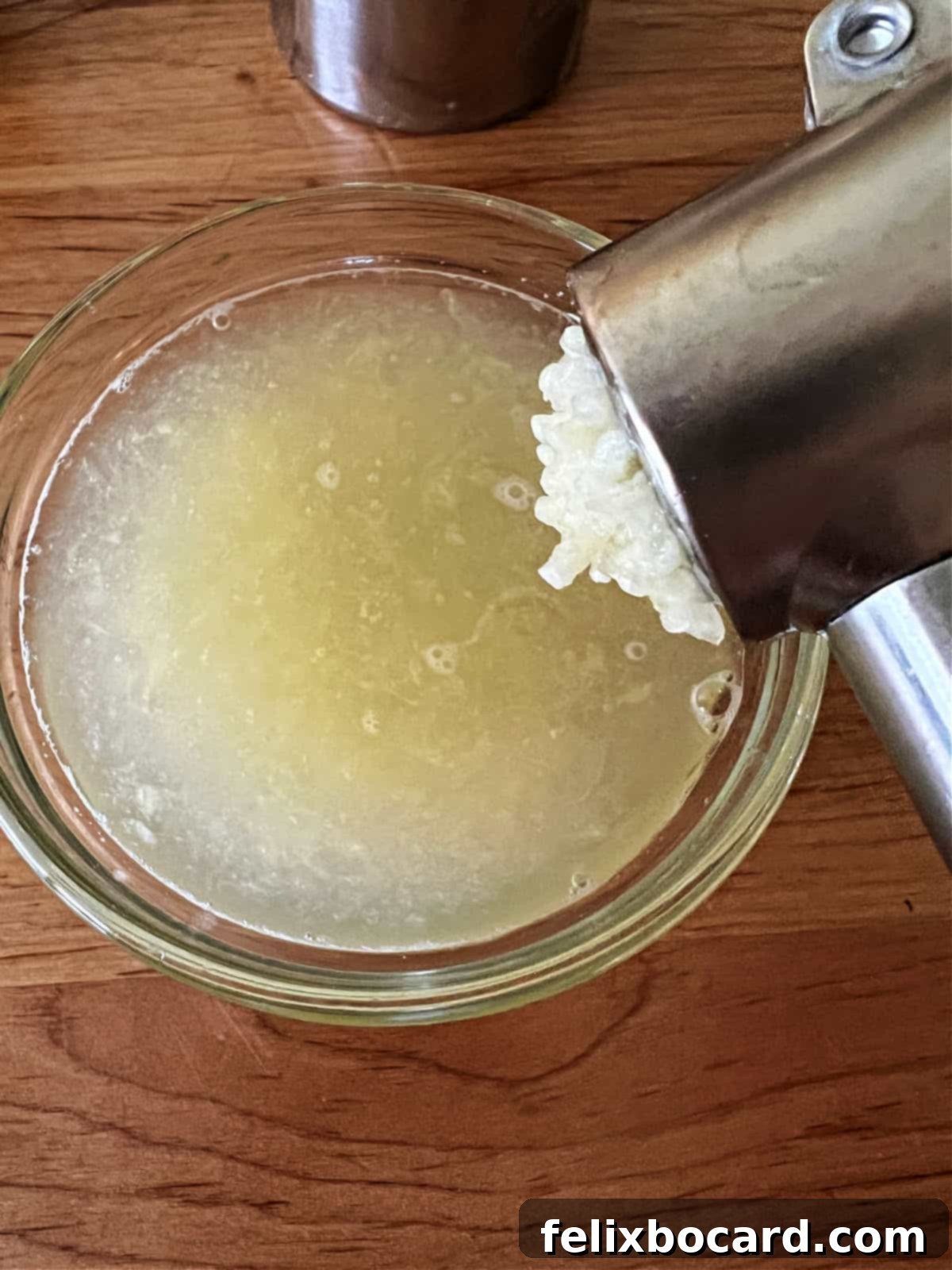 Placing minced garlic in lemon juice to help mellow the bite.
