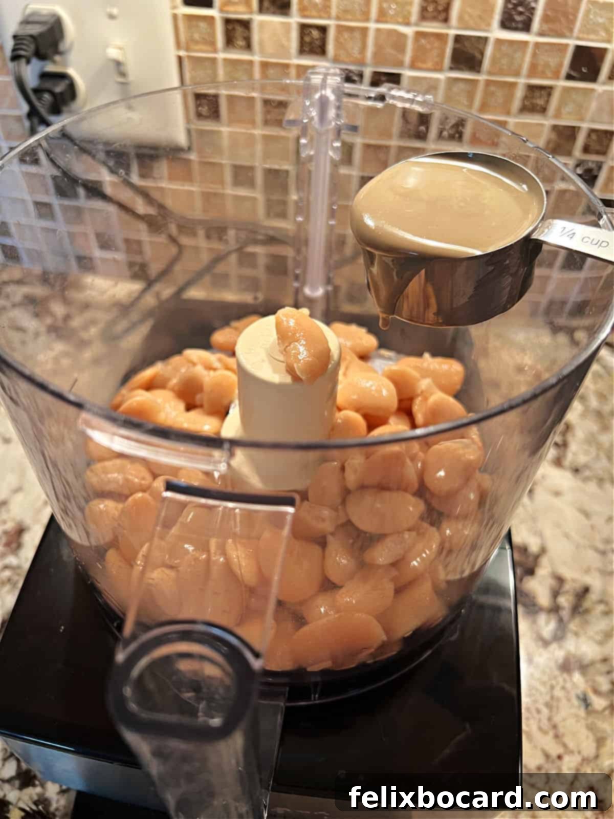 Adding tahini to food processor with butter beans.