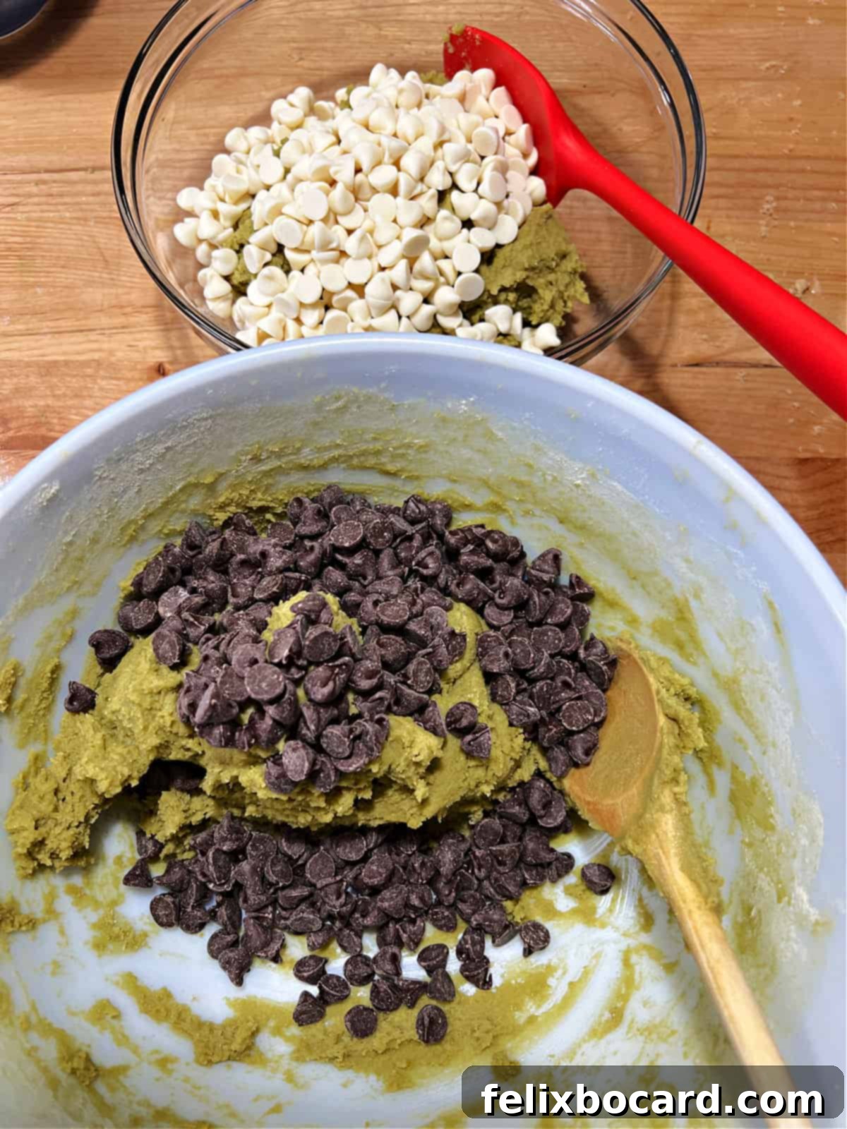 Matcha cookie dough in 2 bowls, one with white chocolate chips and the other with semi-sweet, ready to be stirred in.