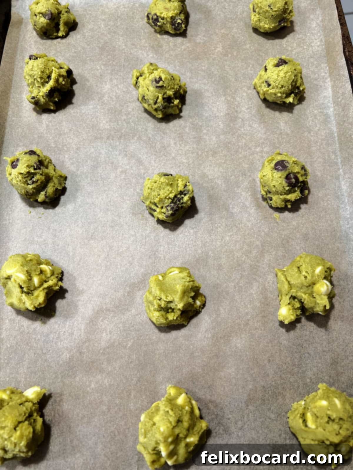 Balls of matcha cookie dough on a baking sheet ready to be baked.