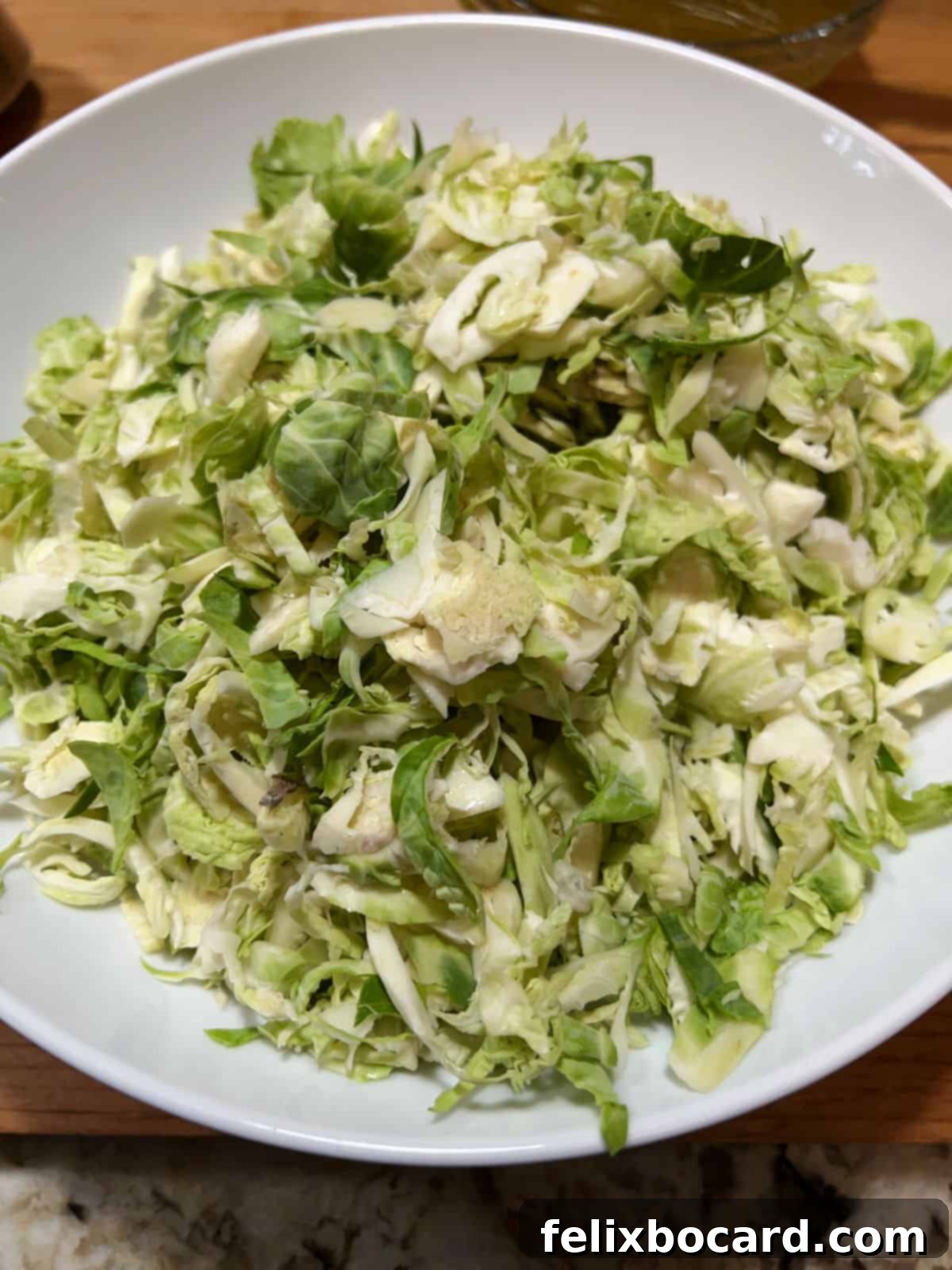 Brussels Sprouts and Cranberry Salad 4 Close-up of finely shredded Brussels sprouts in a bowl, ready for salad preparation.