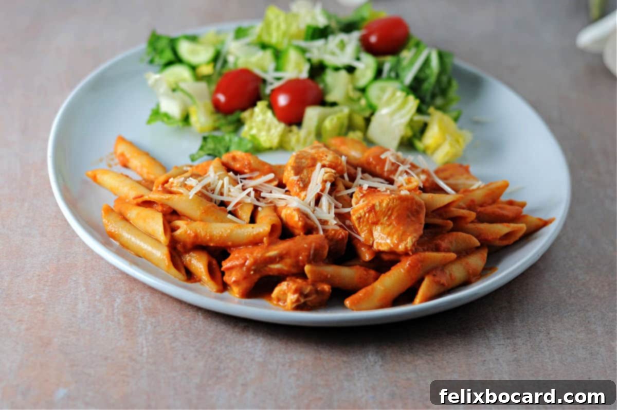 A close-up shot of a plate brimming with creamy penne alla vodka, featuring tender chicken pieces and fresh basil garnish.