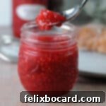 jar of raspberry freezer jam with a spoon holding some above it.