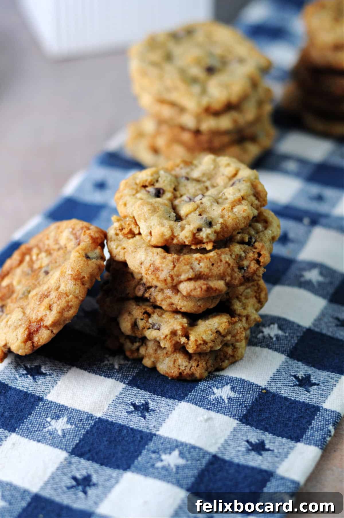 Chocolate Chip Cookies with a Crispy Secret 2 Stack of oatmeal rice krispie cookies on a blue and white checkered towel, showcasing their golden-brown perfection and tempting texture.