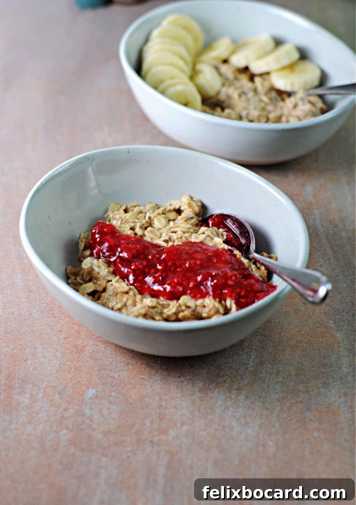 Two appealing bowls of creamy peanut butter overnight oats, one generously topped with fresh banana slices and the other with vibrant raspberry jam, invitingly presented as delicious and healthy breakfast options.