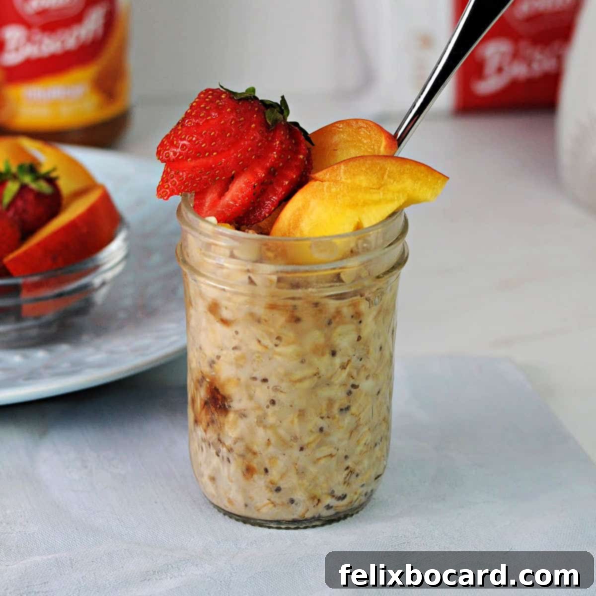 Biscoff overnight oats in a jar garnished with slices of nectarine and a strawberry.
