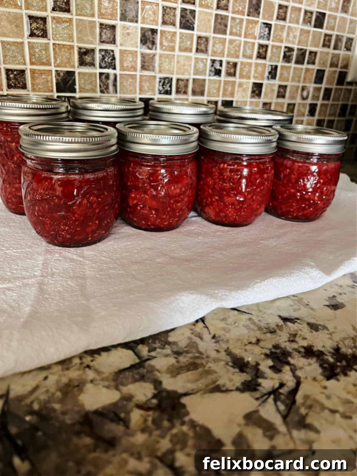 Homemade Reduced Sugar Raspberry Freezer Jam 7 group of filled jam jars cooling at room temperature.