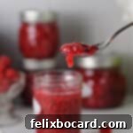 Homemade Reduced Sugar Raspberry Freezer Jam 10 spoon of raspberry jam with a small amount dripping from the edge.