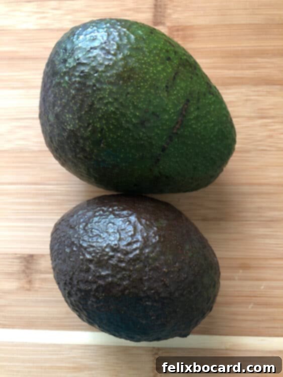 Comparison of an unripe and a partially ripe avocado in a brown paper bag