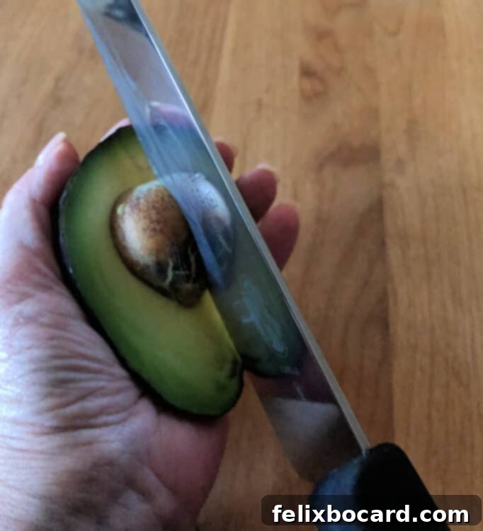 Dangerous method of removing an avocado pit by holding it in hand