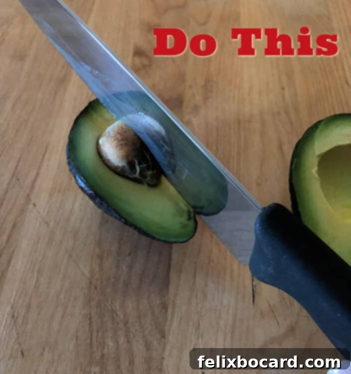Avocado half on cutting board with knife embedded in pit