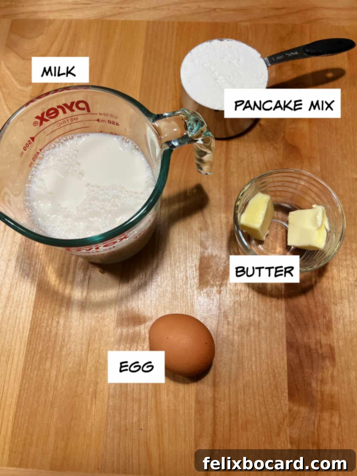Key ingredients for making crepes from pancake mix: milk, pancake mix, melted butter, and an egg, neatly arranged.