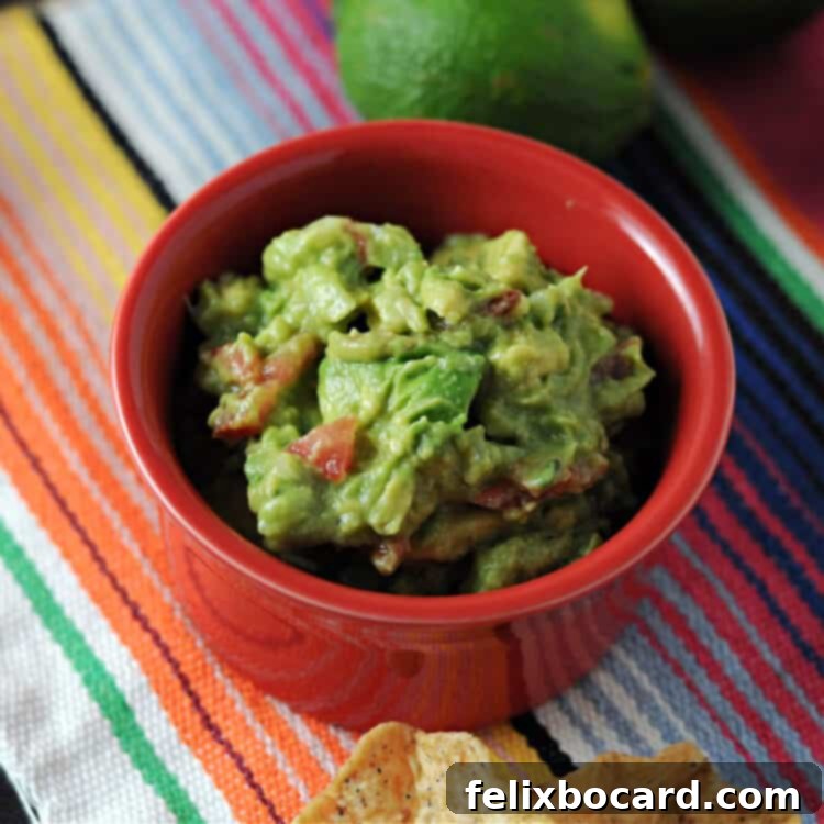 Ultimate Avocado Fiesta 4 Close-up of a small, inviting red bowl of creamy green guacamole, artfully placed on a vibrant, striped blanket, perfect for a snack or party.