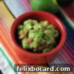 Ultimate Avocado Fiesta 6 A small red bowl of homemade guacamole, set on a bright, striped blanket, inviting you to dip in.