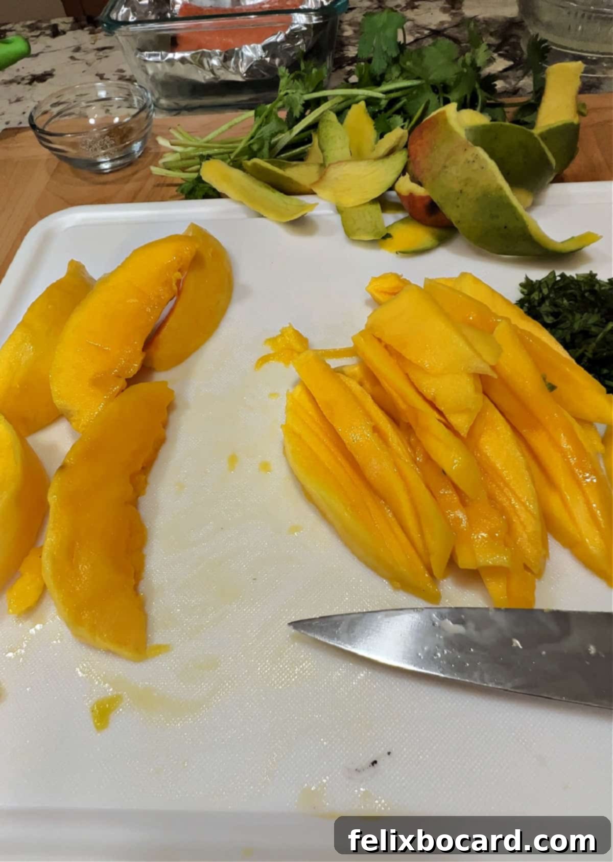 Tropical Mango Slaw for Fish Tacos 4 Close-up of freshly cut mango strips on a white cutting board, showcasing the vibrant orange color and perfect julienne style cut for the slaw.