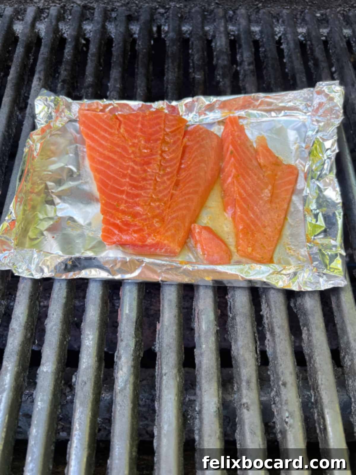 BBQ Salmon Tacos with Tangy Slaw 4 Raw marinated salmon fillets resting in a custom-made foil basket on a BBQ grill.