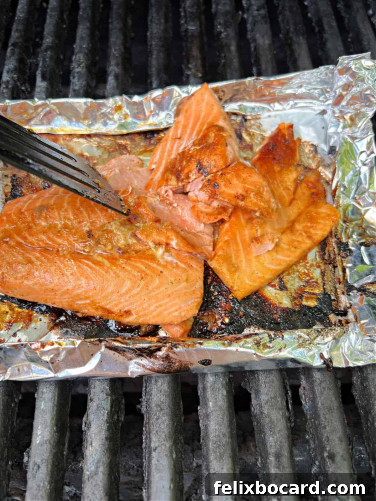 BBQ Salmon Tacos with Tangy Slaw 5 A spatula gently pressing down on cooked salmon, causing it to flake apart easily, indicating perfect doneness.