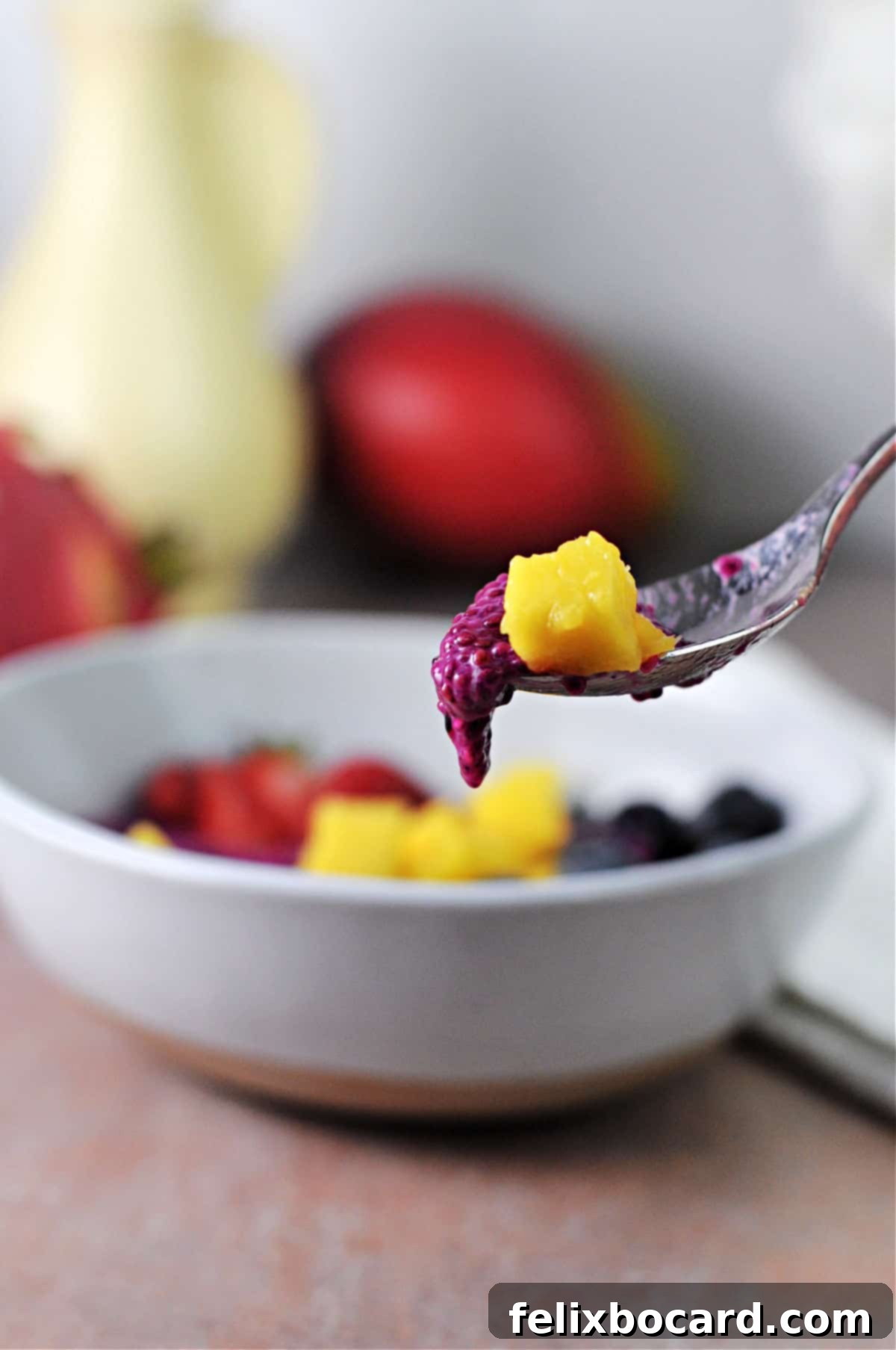spoon holding fruit and chia seed pudding.