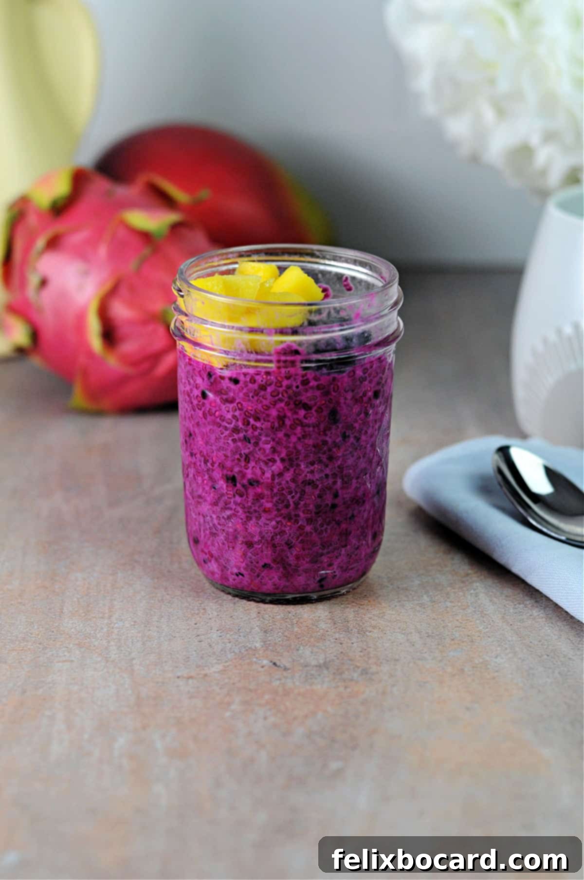 jar of pink chia pudding topped with fruit and ready to eat.