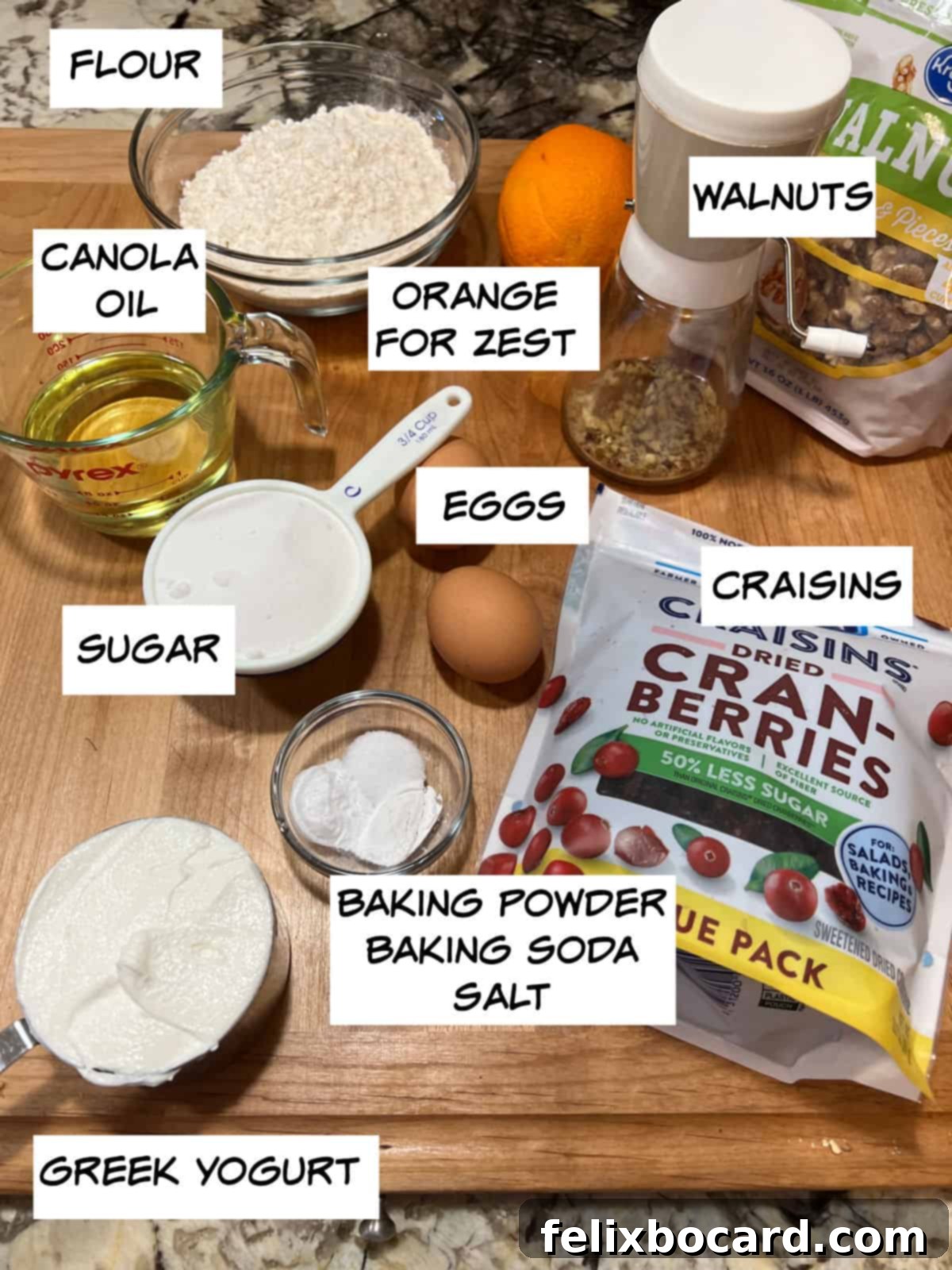 A flat lay of ingredients for cranberry walnut muffins, including flour, oil, walnuts, orange, eggs, sugar, Greek yogurt, baking powder, baking soda, and salt.
