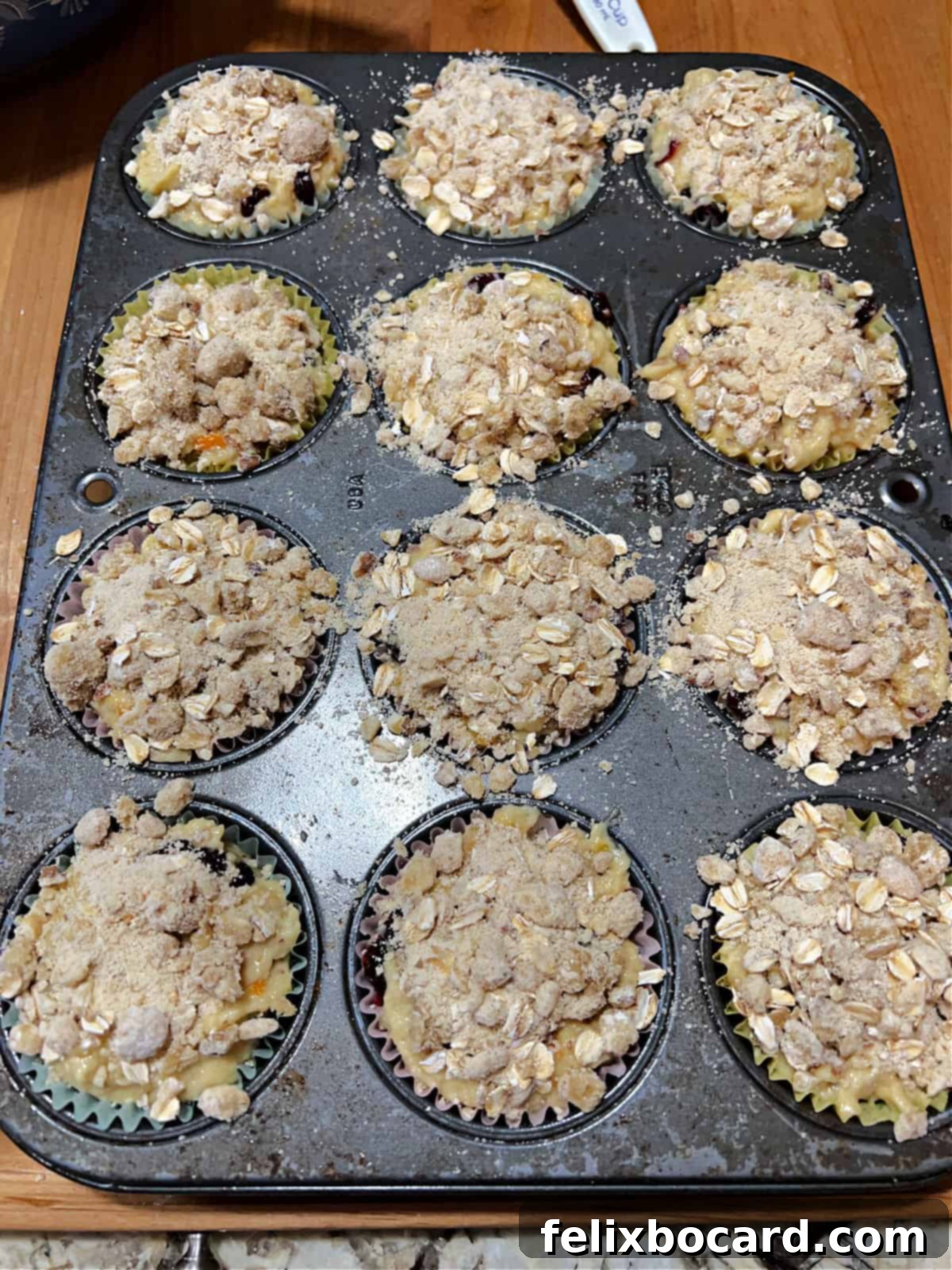 Muffin batter in cups topped with streusel mixture, ready for baking.