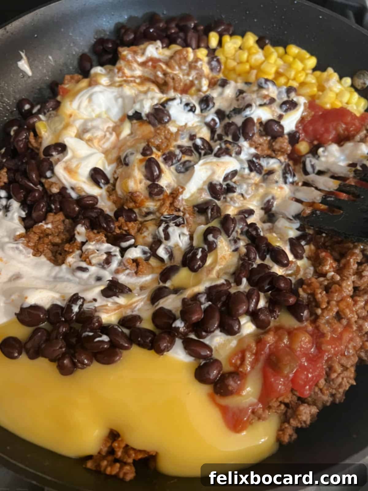 Cheesy Dorito Ground Beef Bake 5 Ground beef, black beans, corn, salsa, soup, and sour cream mixing in a large skillet.