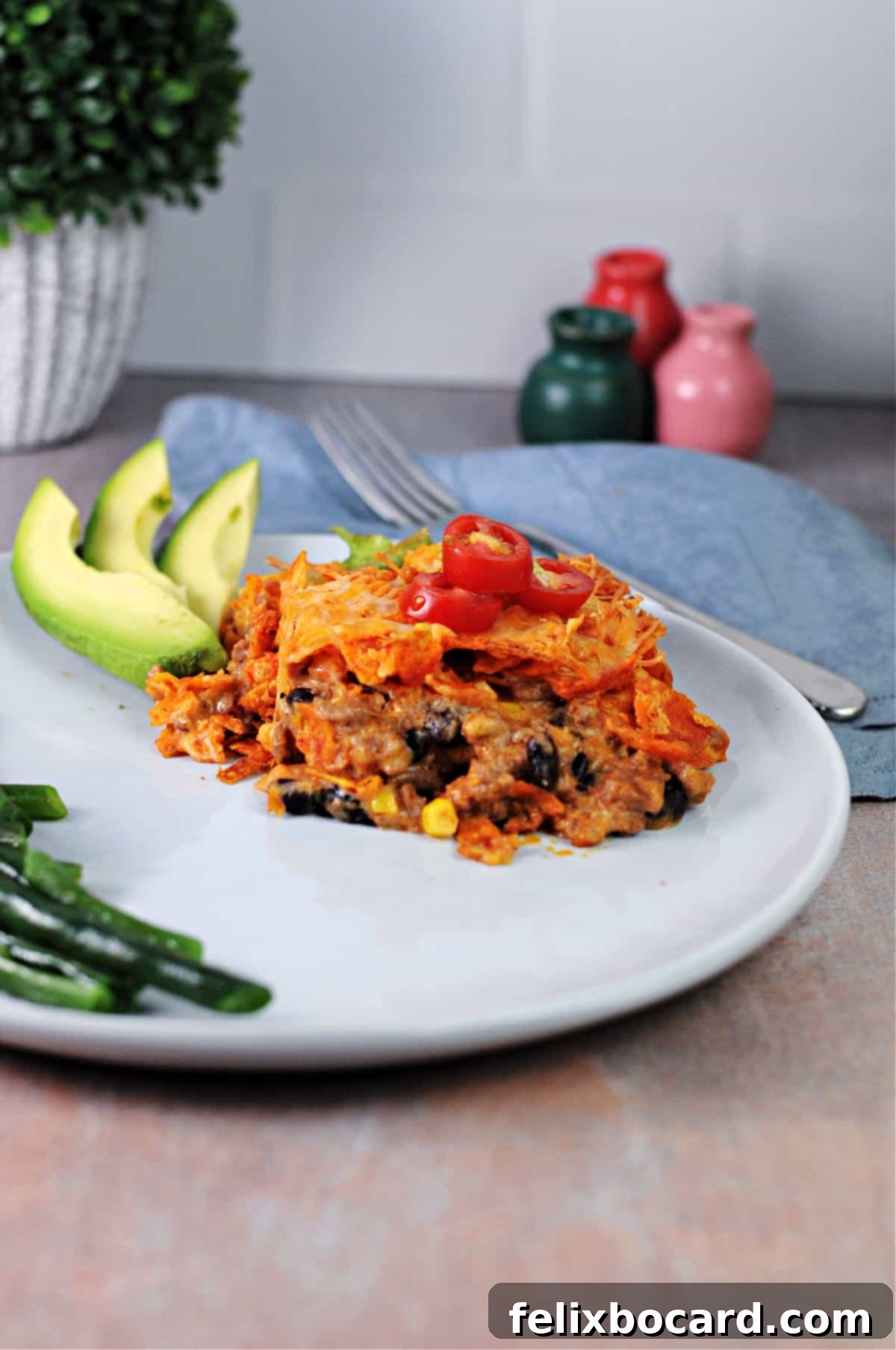 Cheesy Dorito Ground Beef Bake 7 A serving of Dorito casserole on a plate, garnished with fresh avocado slices.
