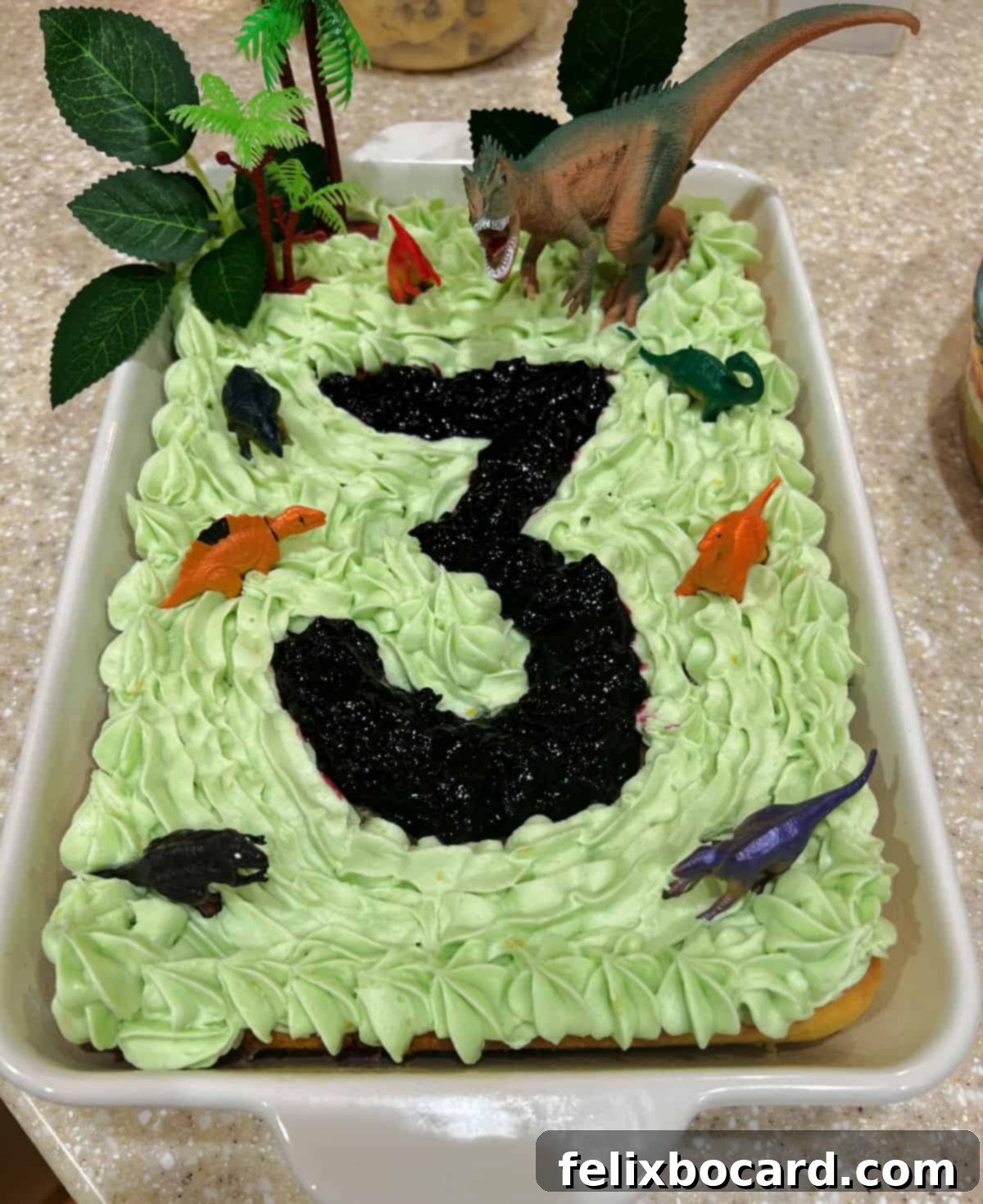 A vibrant '3-Rex' dinosaur-themed birthday cake, featuring a delicious blueberry cake filling shaped into the number three.
