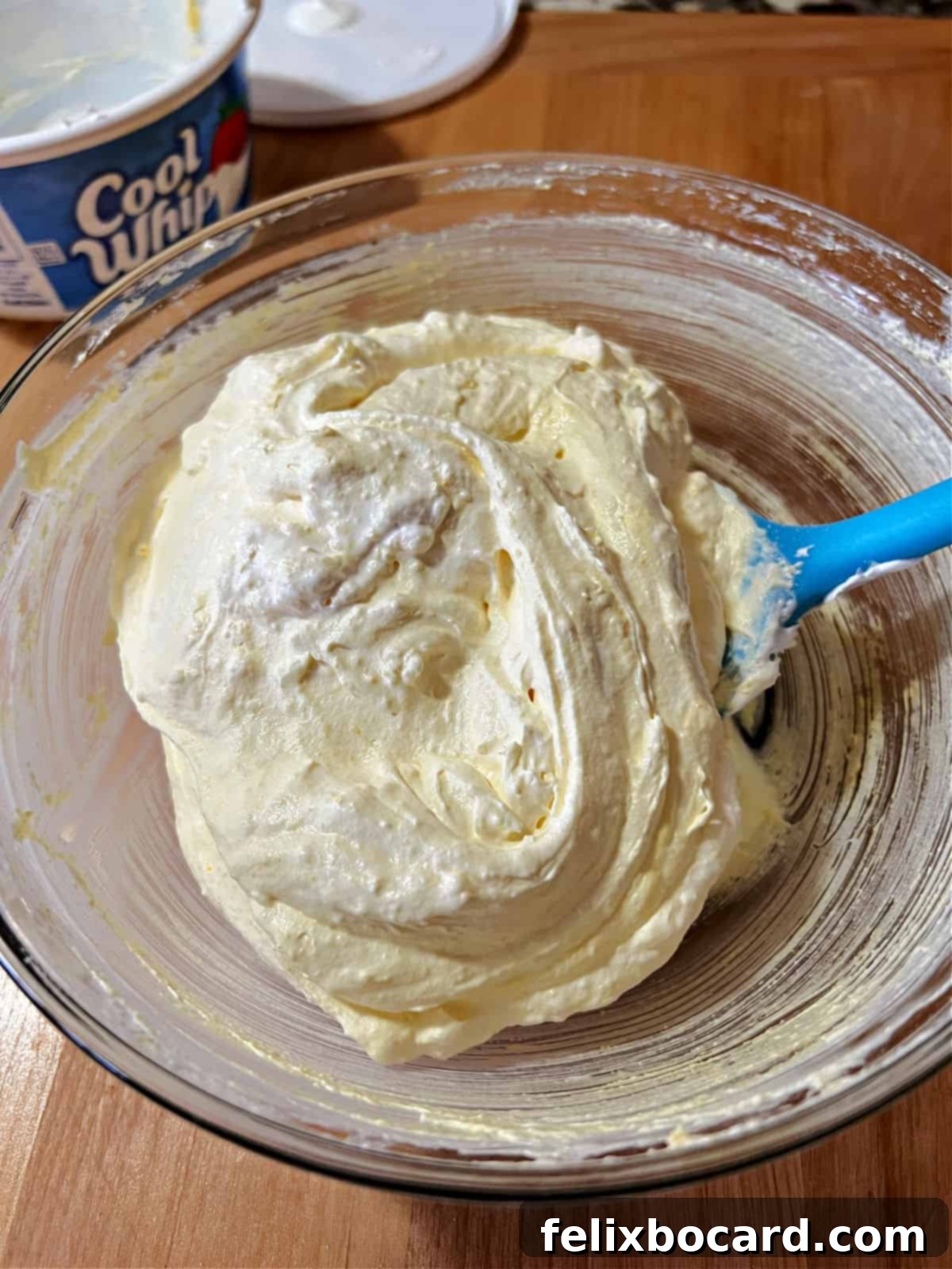 Sweet Cloud Fruit Dip 4 Two ingredients, whipped topping and instant pudding mix, being stirred together in a bowl to make fruit dip.