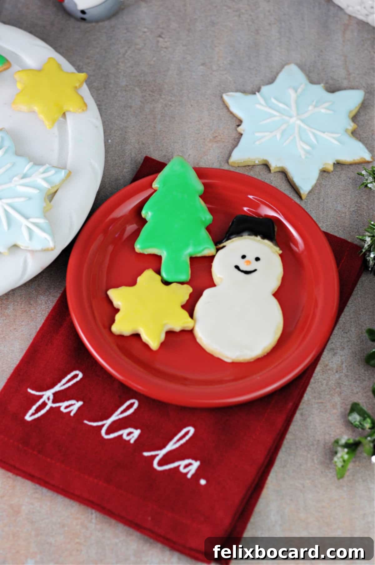 Decorated cut-out sugar cookies on a small red plate, showcasing festive designs.