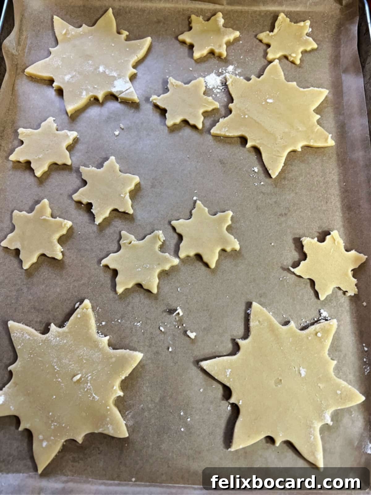 Cut-out cookie shapes neatly arranged on a parchment-lined baking sheet, ready for the oven.