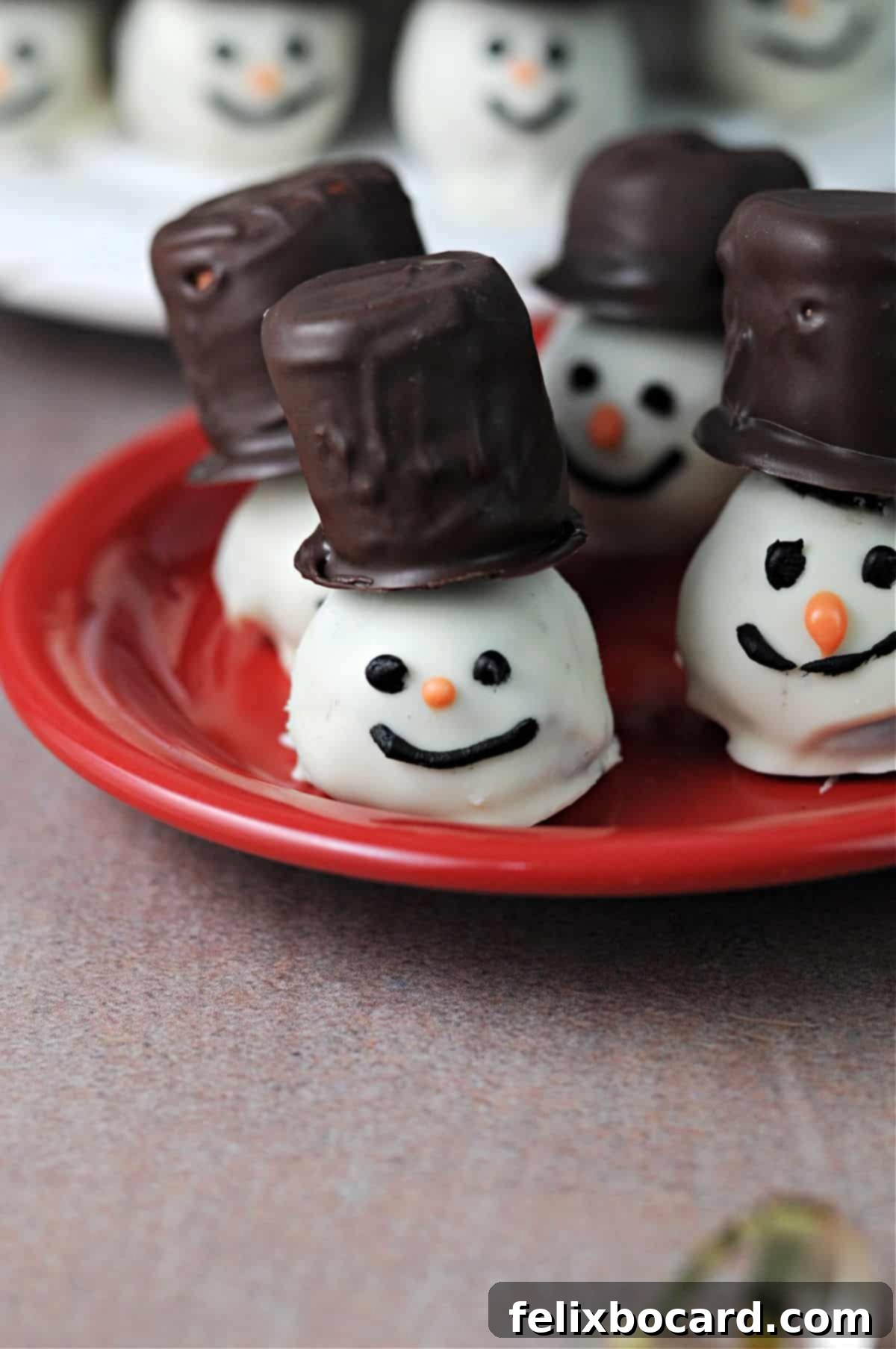 Snowman Oreo Truffles 10 group of snowman oreo balls on a red plate with more behind..