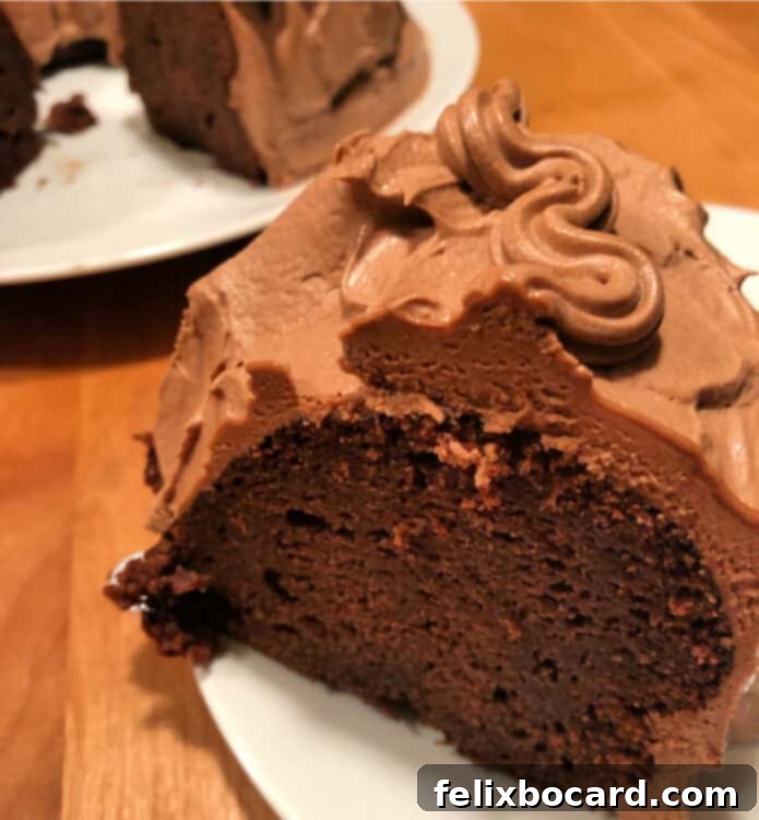 A perfectly sliced piece of Kahlua Chocolate Cake with generous frosting on a white plate