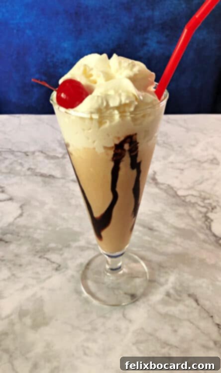 Kahlua Mudslide 2 Kahlua Mudslide ice cream drink in a tall glass topped with whipped cream and a cherry, ready to be enjoyed.