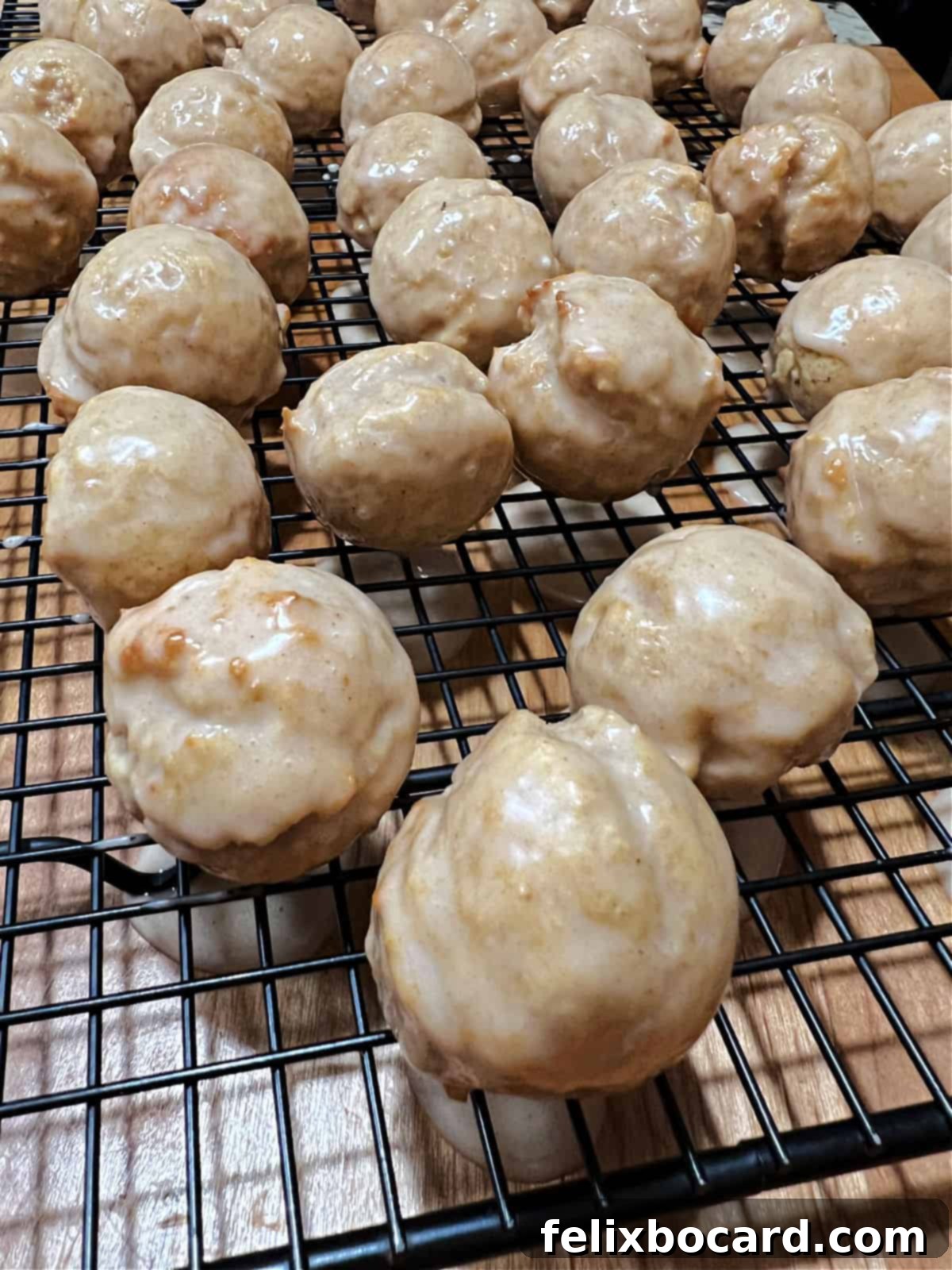 apple cider glazed donut holes drying on a rack.
