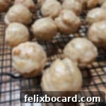 close up of glazed apple cider donut holes on a cooling rack.
