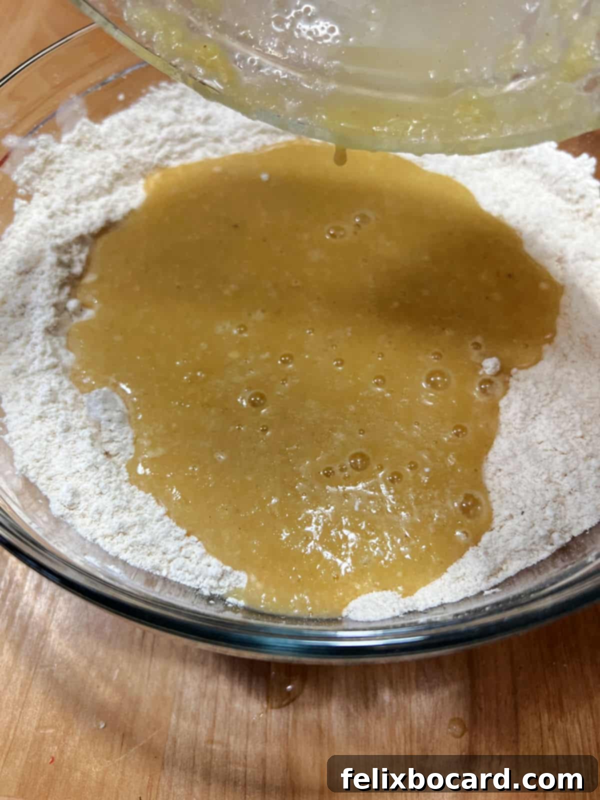 adding wet ingredients to dry in a mixing bowl.