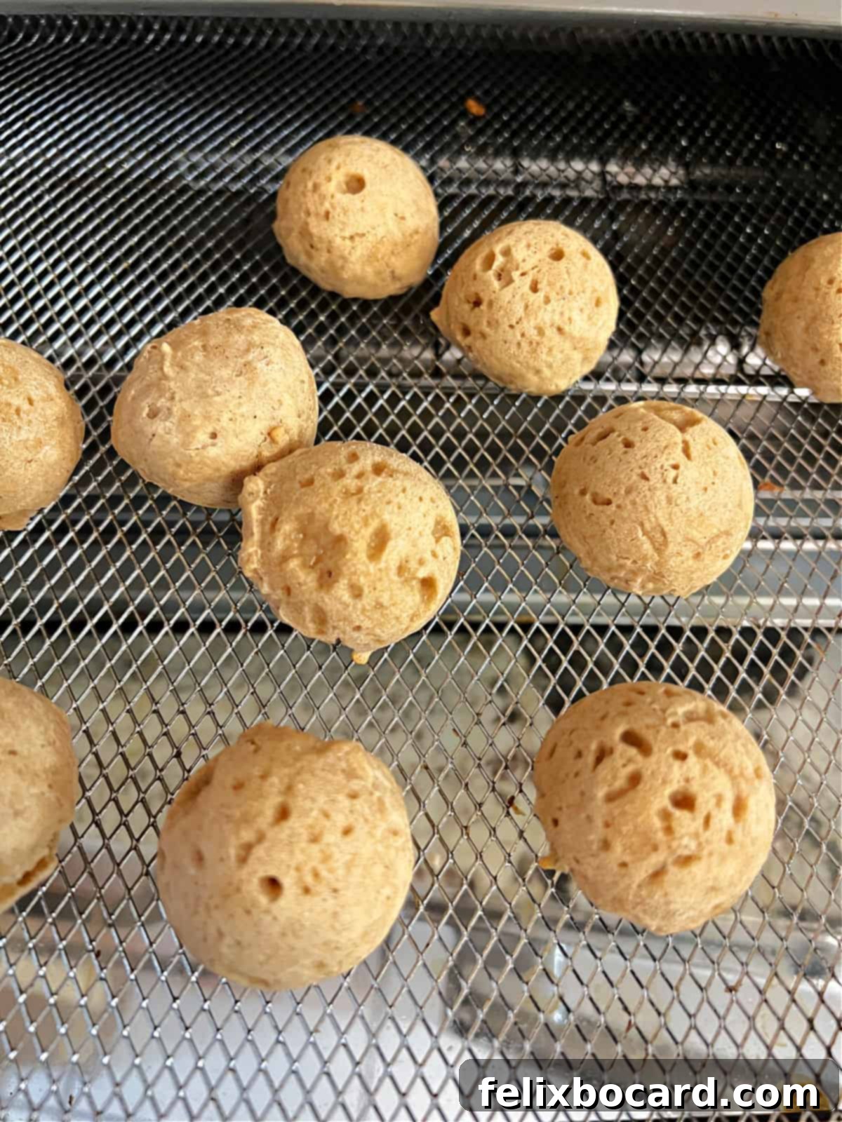 mostly baked donut holes scattered in the air fryer basket.