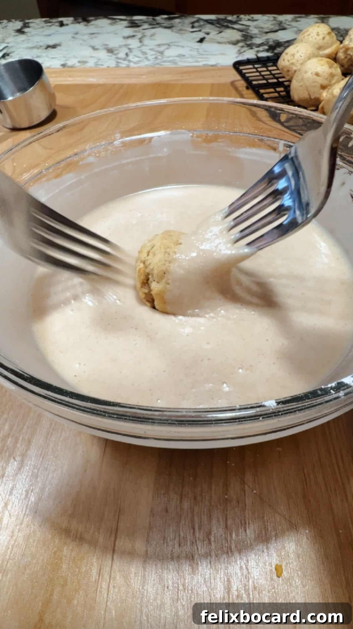 2 forks rotating an air fryer donut hole in the apple cider glaze.